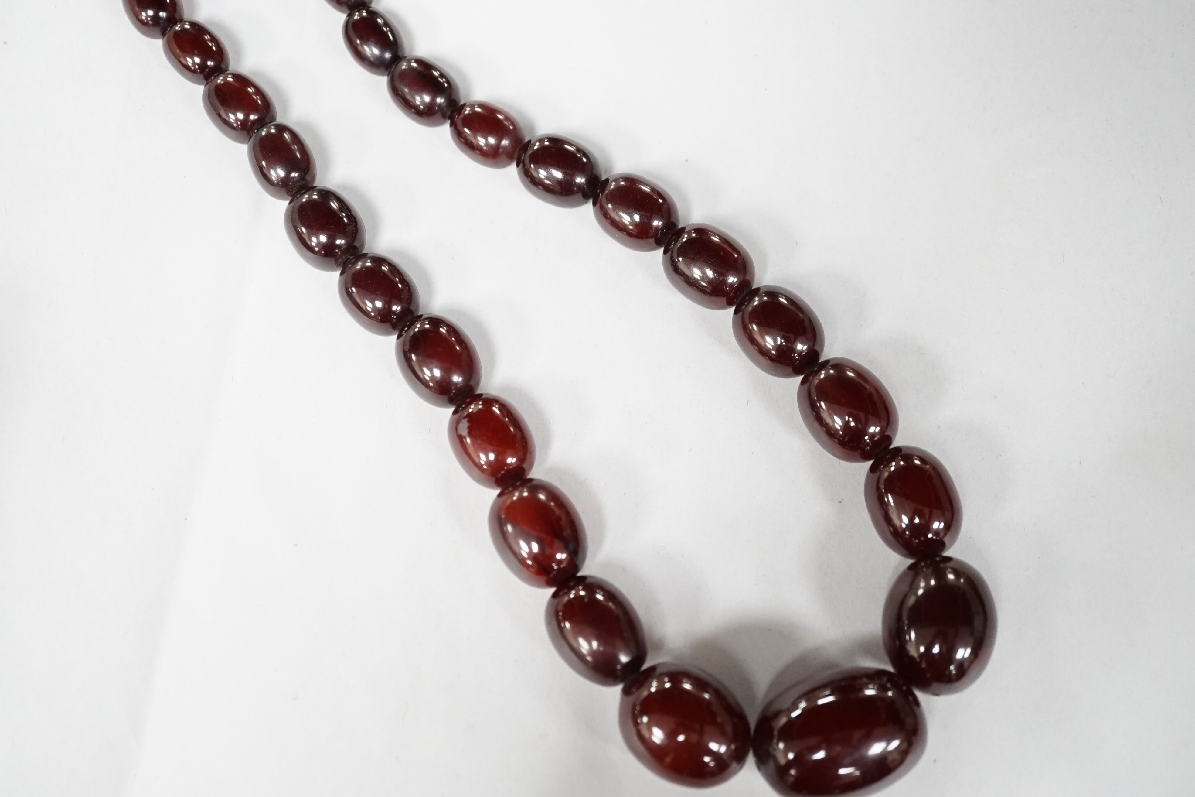 A single strand graduated simulated cherry amber oval bead necklace, 98cm, gross weight 140 grams. Condition - fair to good